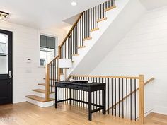 the stairs are made of wood and have black railings on each handrail, along with a white painted wall