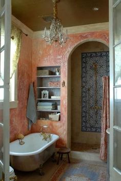 a bath tub sitting under a chandelier in a bathroom