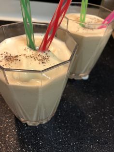 two glasses filled with milk and straws on top of a counter