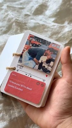 a hand holding a small card with an image of two people on it