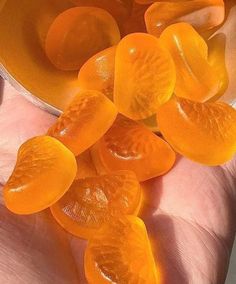 a person is holding some orange jelly in their hand and it looks like they have been sliced