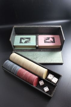 two playing cards and dice in a box on a black surface with other items inside