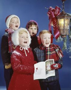 four children are posing for a photo in front of a christmas ornament and lantern