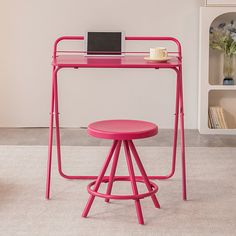 a pink desk with a laptop on it and a stool in front of the desk