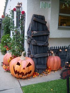 two pumpkins sitting on the ground in front of a house with halloween decorations around them