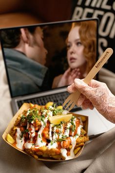 a person holding a fork and knife over a plate of food with a laptop in the background