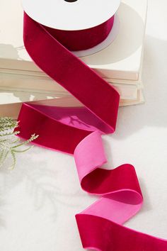 a roll of pink satin ribbon next to a stack of books