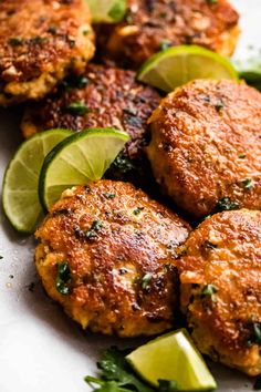 several crab cakes with limes and cilantro on a plate