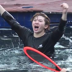 a woman is in the water with a frisbee and her arms are up