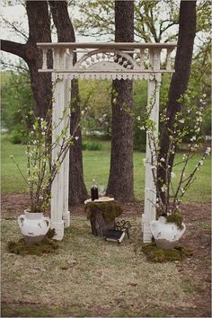 an outdoor wedding ceremony setup with white flowers and greenery on the ground, surrounded by trees