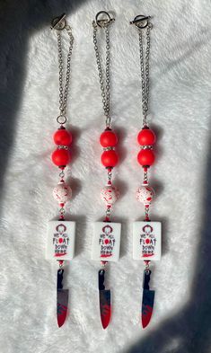 four red and white necklaces hanging from chains on top of a snow covered ground