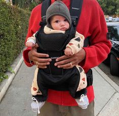 a man holding a baby in a carrier