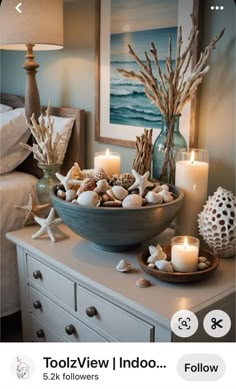 a bowl filled with seashells sitting on top of a dresser next to candles