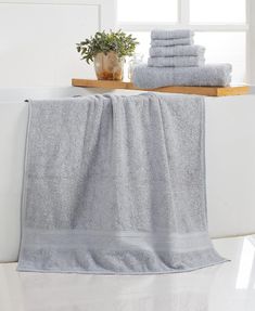 a stack of towels sitting on top of a bath tub next to a potted plant