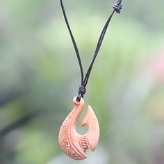 a wooden pendant hanging from a black cord with an animal head on it's side