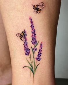 a tattoo with two bees on it and lavender flowers in the foreground, behind which is a bee