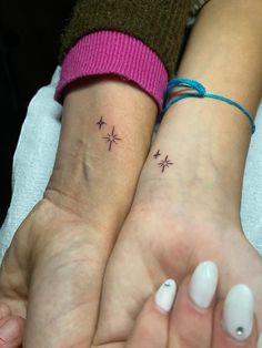 two people with matching tattoos on their wrists, one has a cross and the other has a star