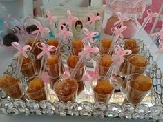 there are many desserts in cups on the tray with pink ribbons and bowknots