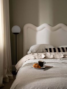 a cup of coffee sits on the edge of a bed next to an empty plate