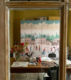 a table with flowers and pictures on it in front of a mirror that is reflecting the room