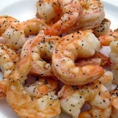 some shrimp on a white plate with black pepper sprinkled on it and seasoning