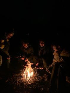 people sitting around a campfire in the dark