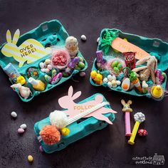 two plastic trays filled with different types of candies and other items on a table