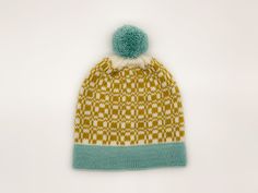 a knitted hat with a pom - pom on the front and side