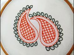 a close up of a embroidery design on a white cloth with orange and black designs