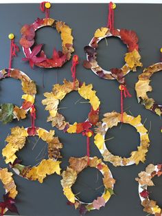 a group of wreaths made out of leaves hanging from strings on a gray wall