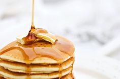 a stack of pancakes covered in syrup on a white plate with a fork sticking out of the top