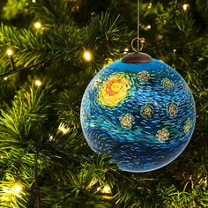 a glass ornament hanging from a christmas tree decorated with stars and the starry night