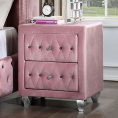 a pink velvet nightstand with two drawers and a clock on the end table next to it