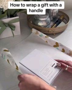 someone is wrapping a gift with a handle on the table next to some flowers