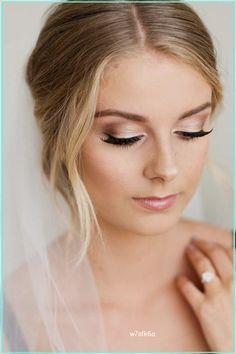 a woman wearing a wedding veil with her eyes closed and makeup applied to the bride's face