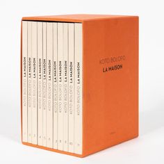 an orange box with six books in it on a white surface, including the title'la maison '