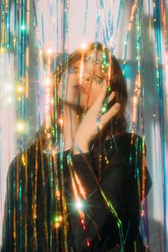 a woman with her hands on her face in front of colorful lights and streamers