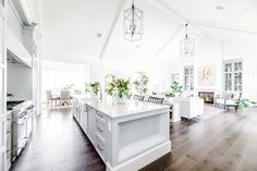 a large open concept kitchen with white cabinets and an island in the middle, surrounded by wood flooring