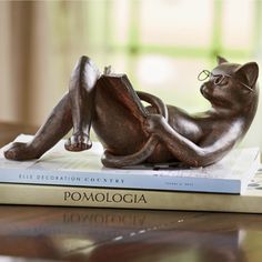 a cat figurine sitting on top of a book next to a pair of glasses