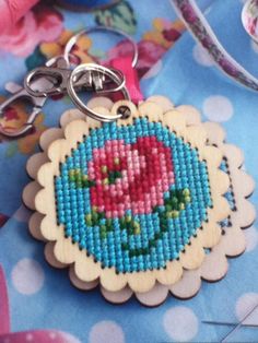 a cross stitch keychain with a pink flower on it's center piece