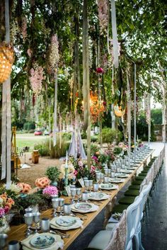 a long table set up with plates and place settings for an outdoor dinner party in the garden