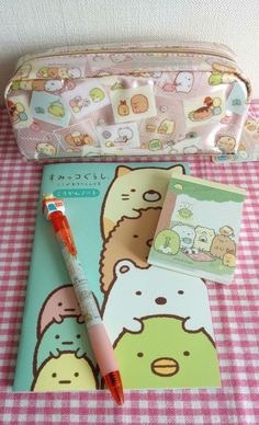 a pink pen sitting on top of a notebook next to a hello kitty pencil case