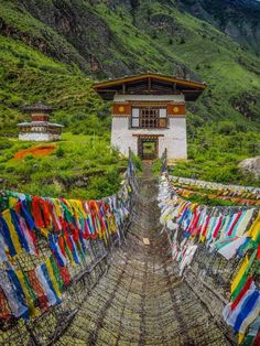 there are many colorful flags hanging on the clothes line in front of a building with a mountain behind it