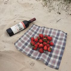 strawberries on a towel with a bottle of wine in the sand