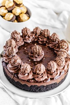 a chocolate cake sitting on top of a white plate next to a bowl of cookies