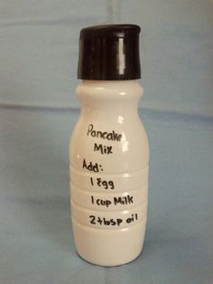 a white ceramic bottle with black lid and writing on it that says pancake mix add 1 cup milk 2 cups oil