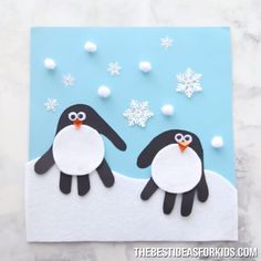 two penguins are standing in the snow on a blue and white background with small balls