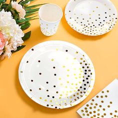 polka dot plates and napkins on an orange surface with pink flowers in the background