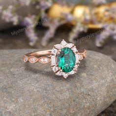 an oval emerald and diamond ring on top of a rock