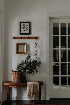 there is a potted plant sitting on the bench in front of the door and framed pictures